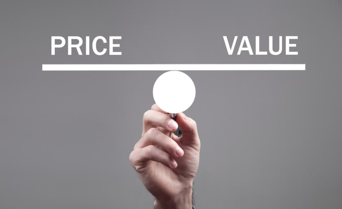 A hand holds a circular object centered between the words PRICE and VALUE on a gray background, symbolizing balance.