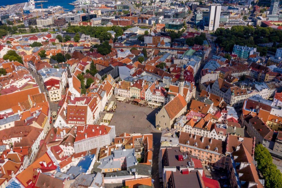 Aerial view of a vibrant cityscape with historic buildings, including towers and rooftops under a dramatic sky.